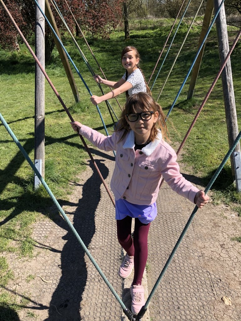 Two young girls standing on a rope swing
