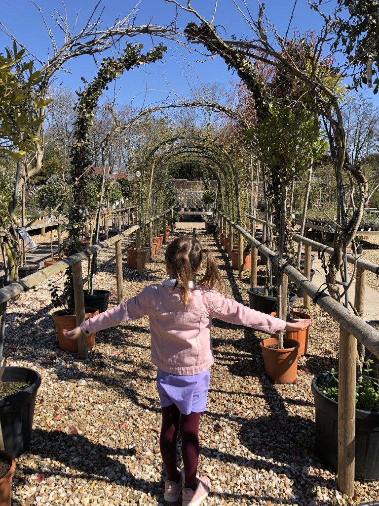 young girl walking under plant arches
