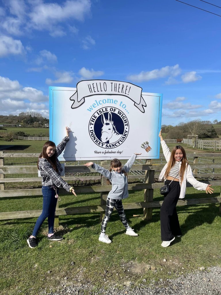 a mum and two daughters in front of the Isle of Wight donkey sanctuary