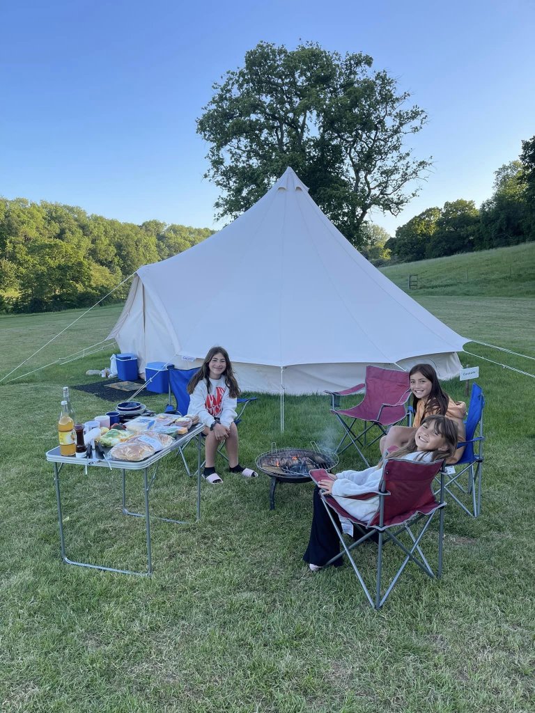 three girls on camping chairs outside the bell tent