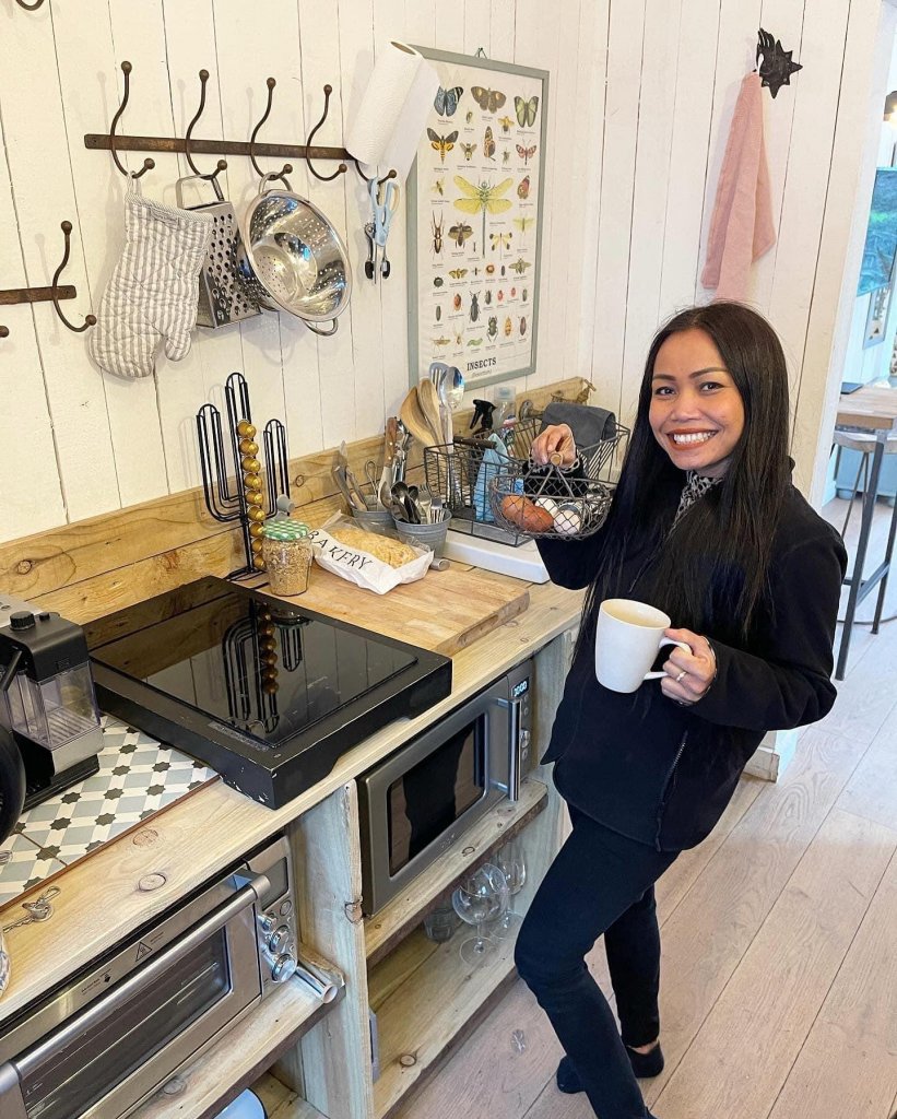 a woman holding a cup of coffee in the kitchen of the barn