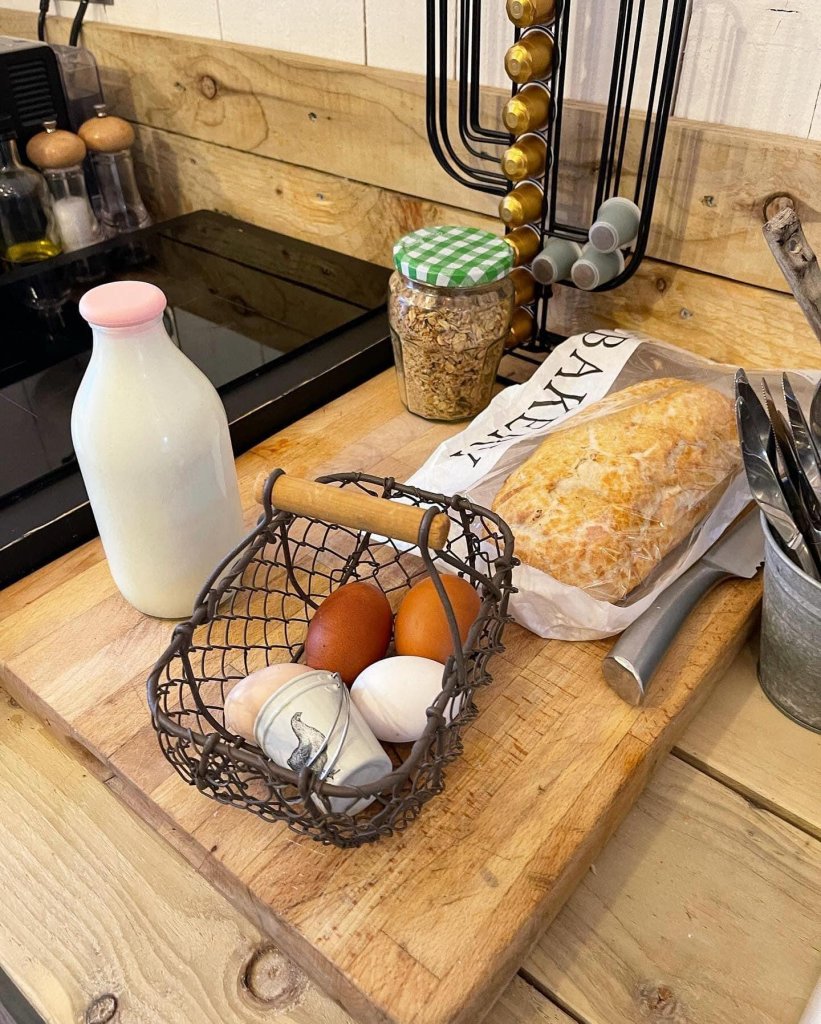 fresh eggs in a basket, a bottle of milk, a jar of spread and fresh bread on a chopping board